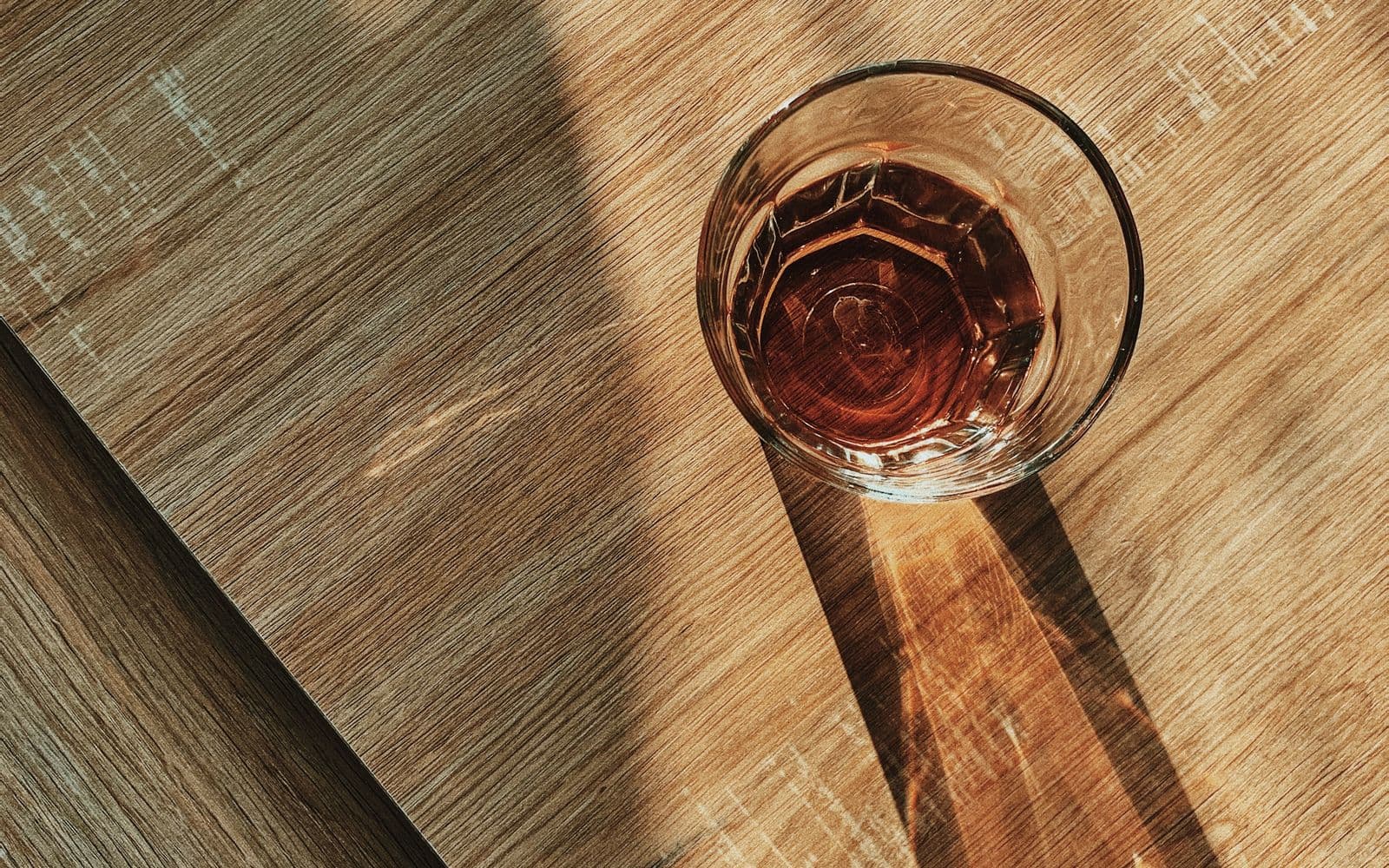 A clear glass of water catching sunlight on a wooden table