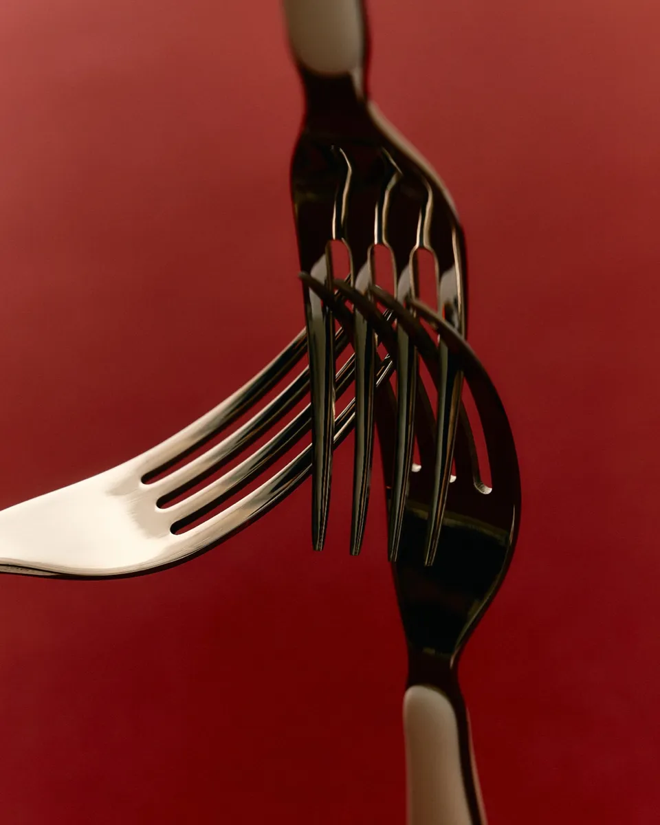 Two forks interlocked against a deep red background