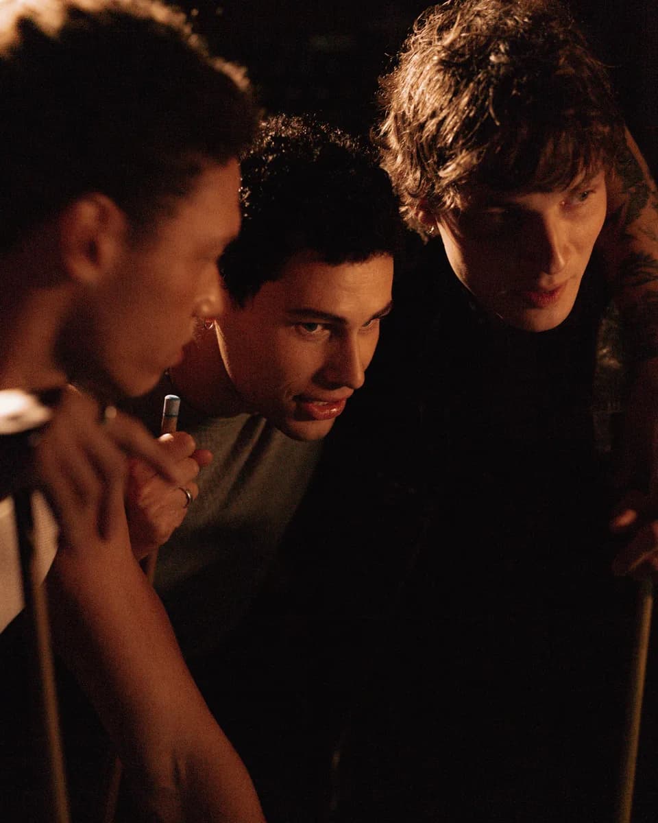 Three friends leaning in together in warm low light