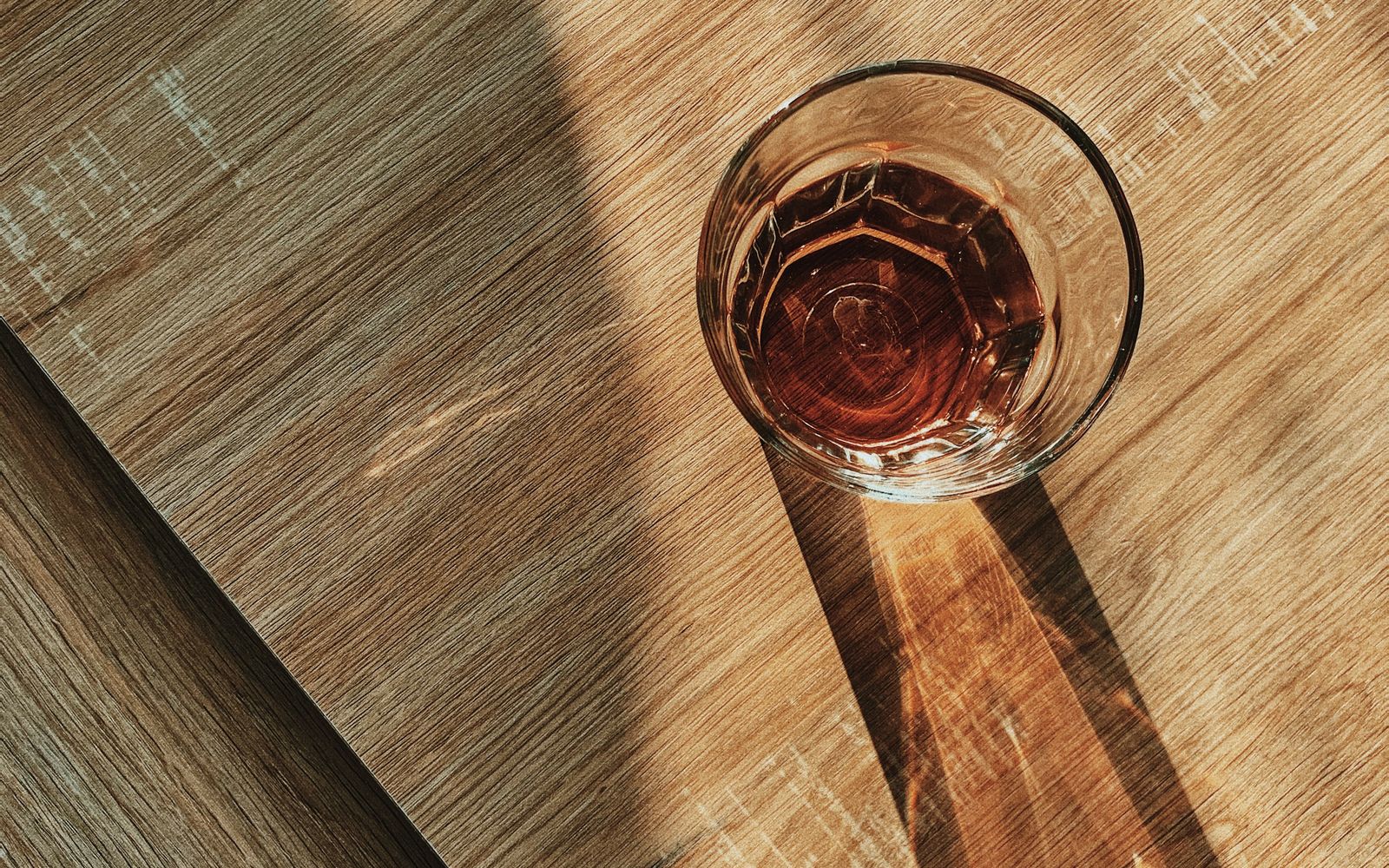 A clear glass of water catching sunlight on a wooden table